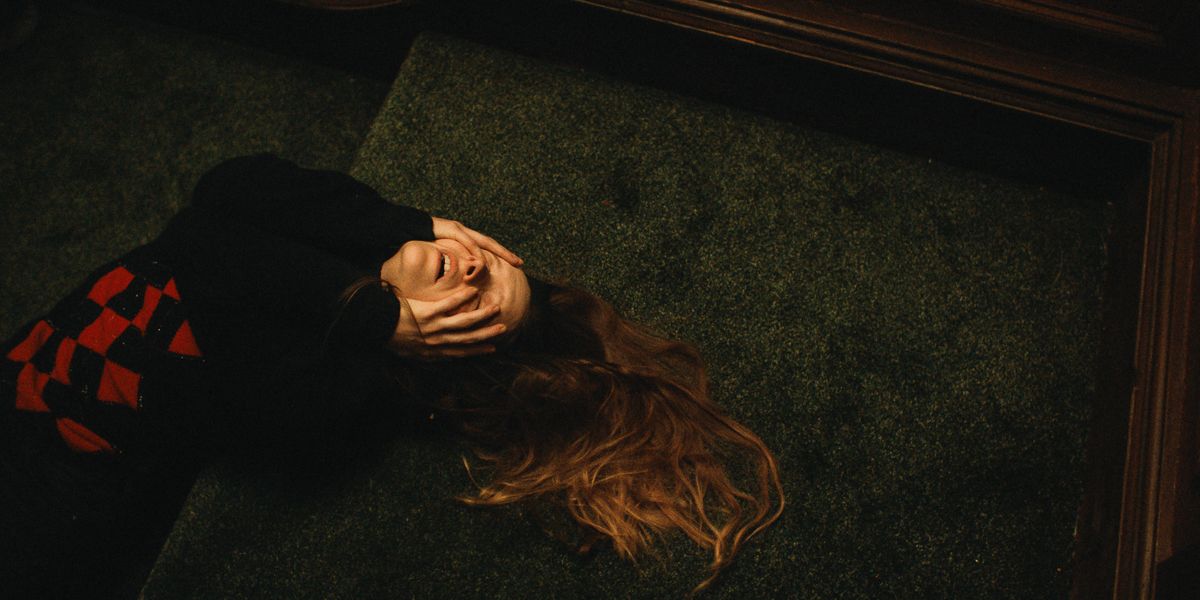 A woman on the floor, covering her eyes