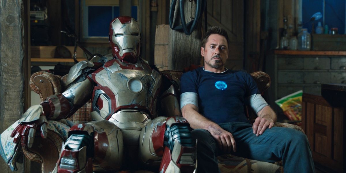 Robert Downey Jr. as Tony Stark sitting next to his armor in Iron Man 3