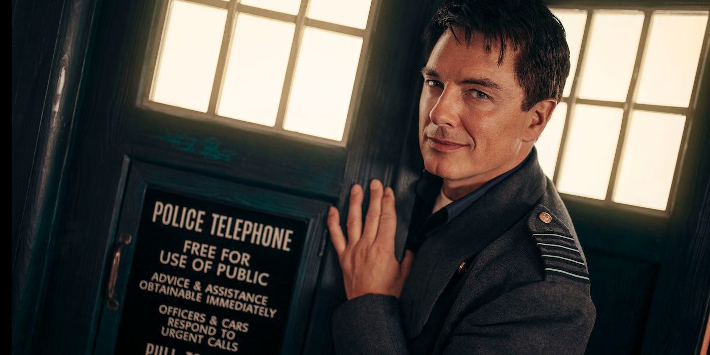 John Barrowman is Captain Jack Harkness on Doctor Who, leaning on the Tardis