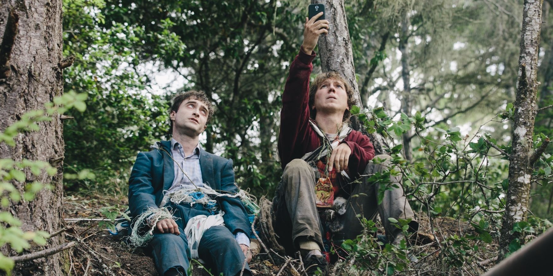 Two dishevelled men sit in the woods in the film Swiss Army Man