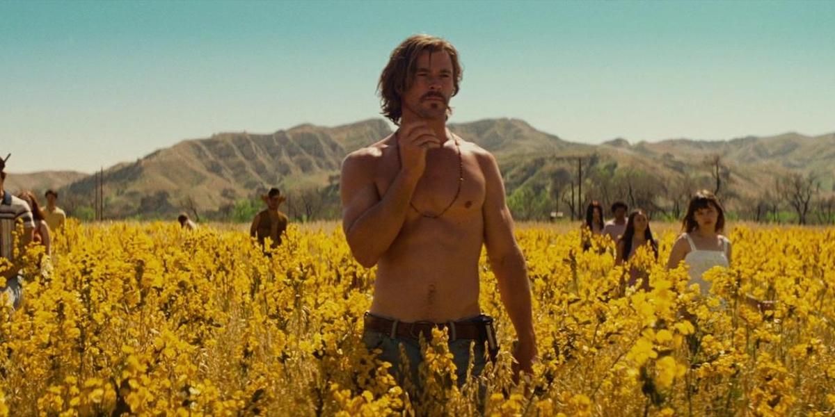 A shirtless man standing in a field