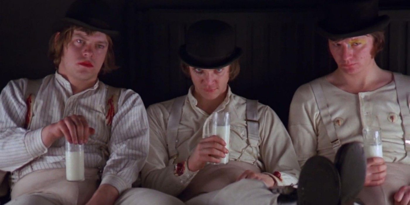 Alex (Malcolm McDowell) and his two Droogs sit with glasses of milk staring at the camera in A Clockwork Orange.