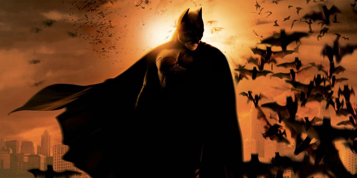 Batman surrounded by bats with Gotham City in the background in Batman Begins.