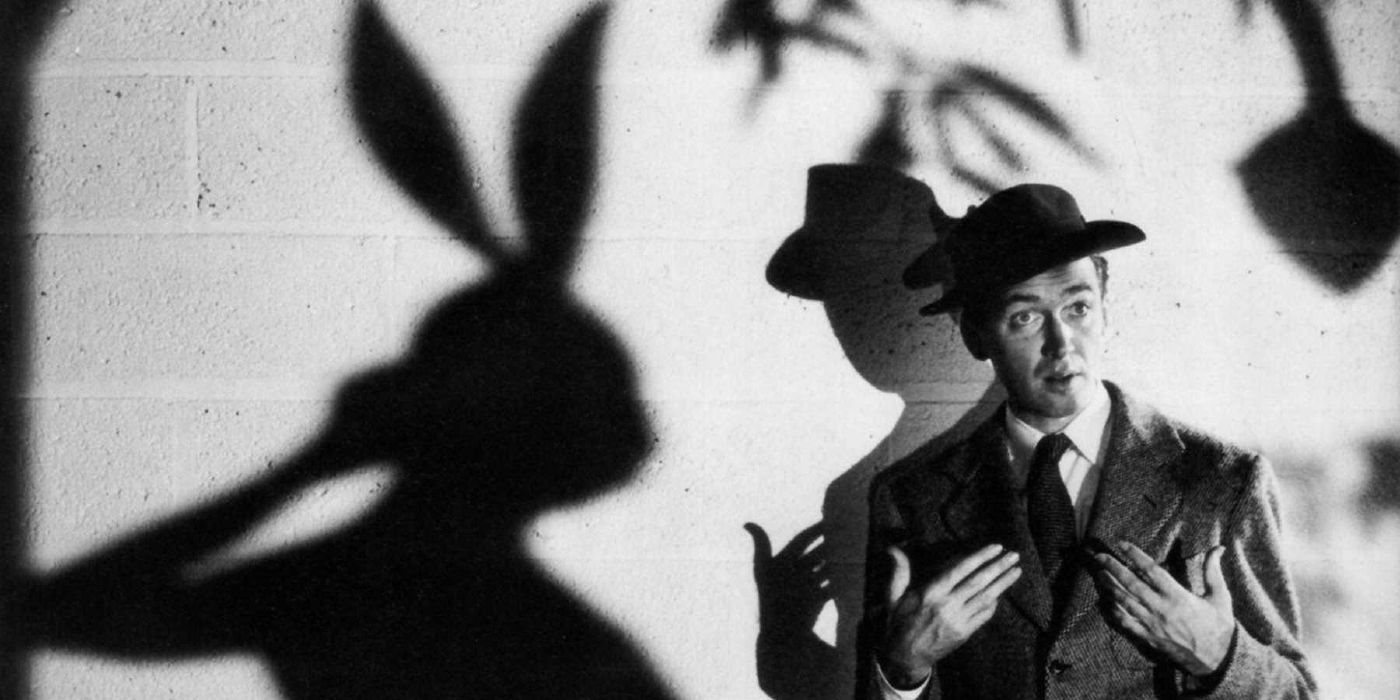 James Stewart stands in front of a brick wall with the shadow of a large rabbit behind him in Harvey.