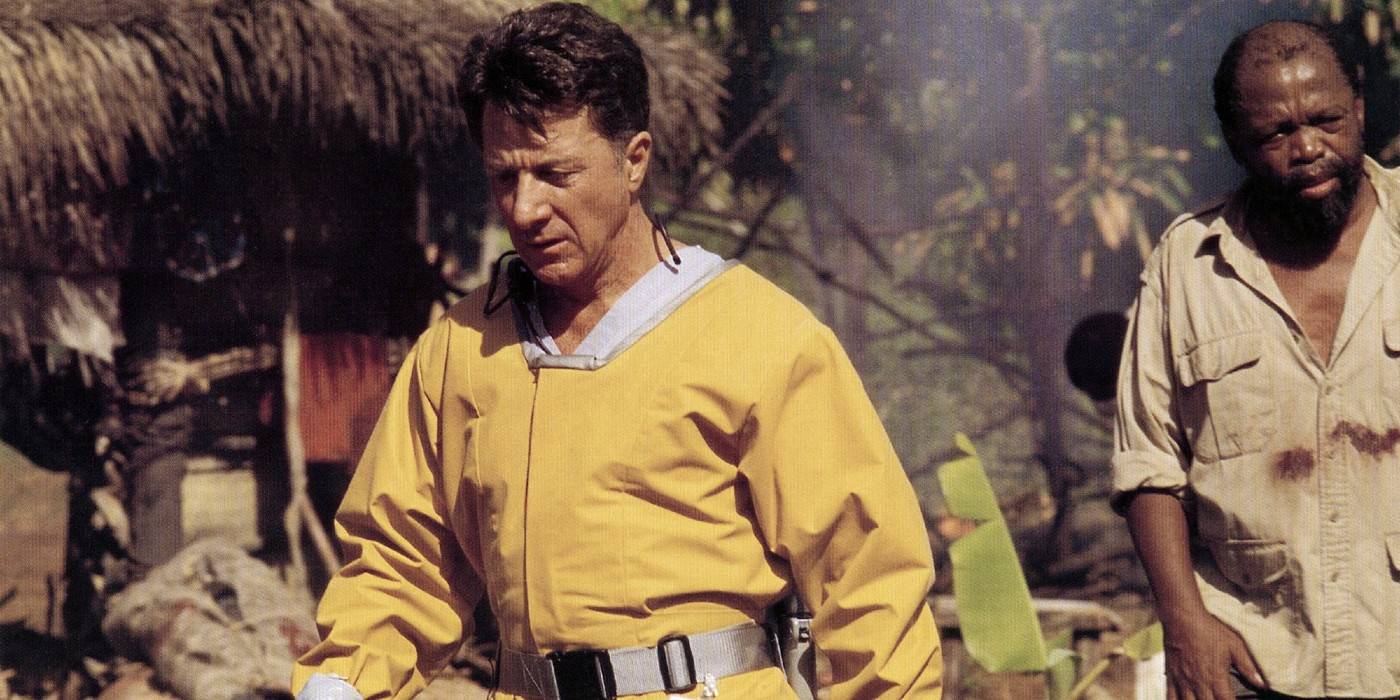 A white man in a yellow hazmat suit with tropical imagery behind him. A Black man stands to the side, wearing a dirty beige top.