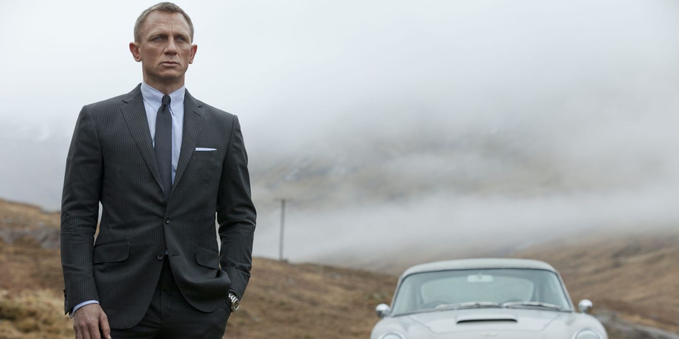 James Bond (Daniel Craig) stands in the misty Scottish countryside wearing a sharp suit.