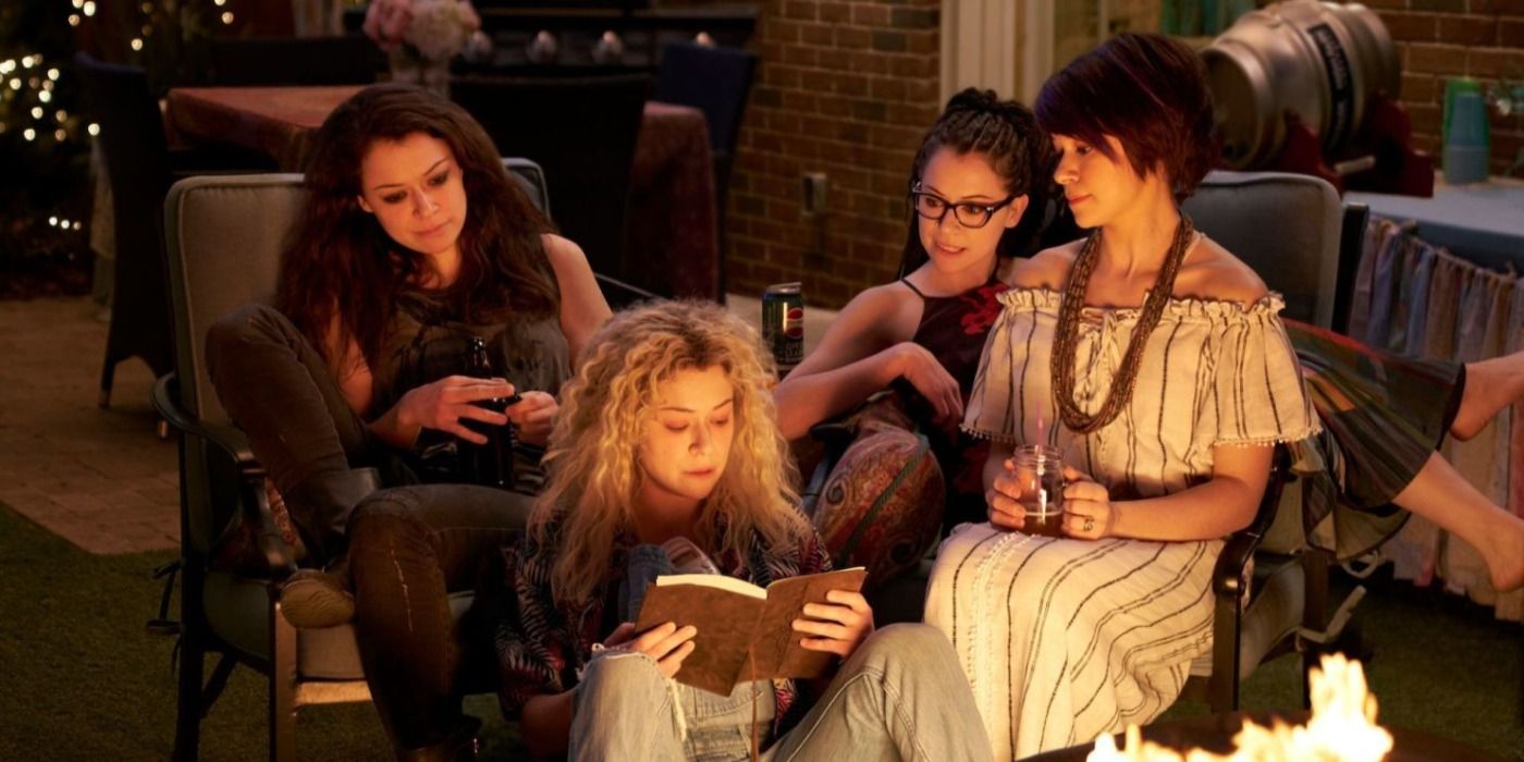 The clones sit together by a fire in Orphan Black