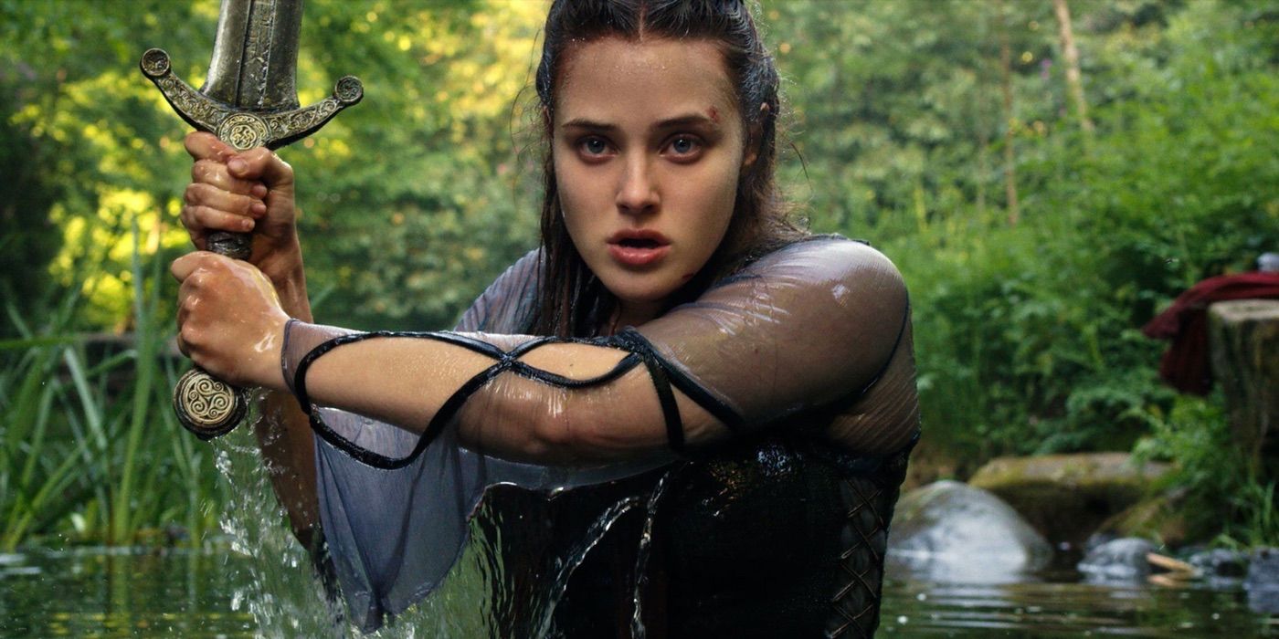 A young woman coming out of a lake holding a sword in the show Cursed.