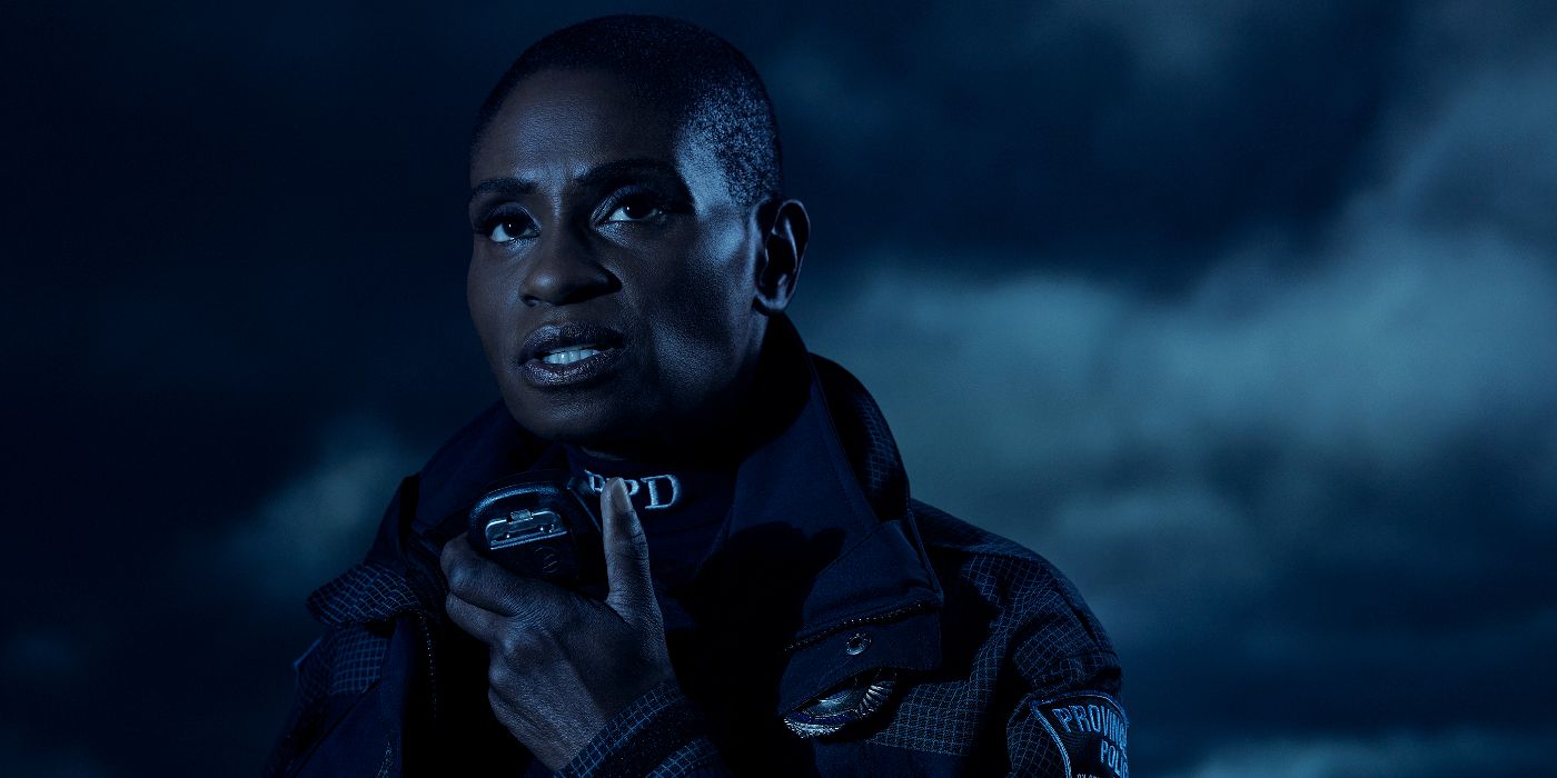 A female cop holding a radio and looking up in AHS Double-Feature.