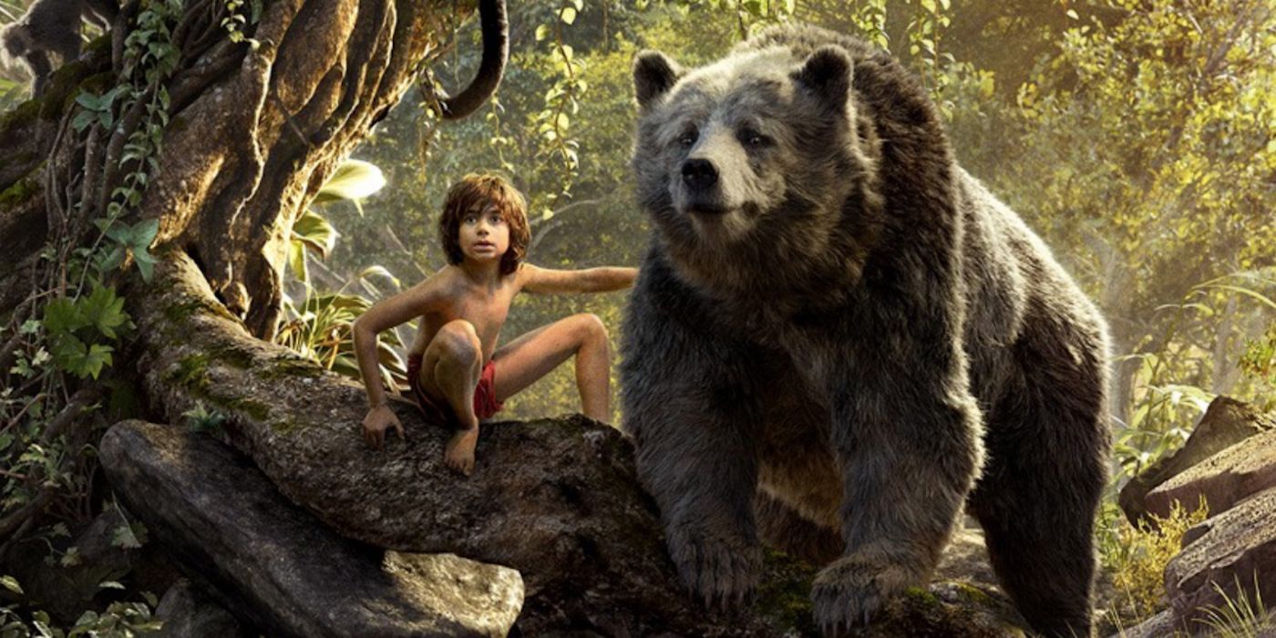 Mowgli sits on a tree branch with his hand on Baloo the bear