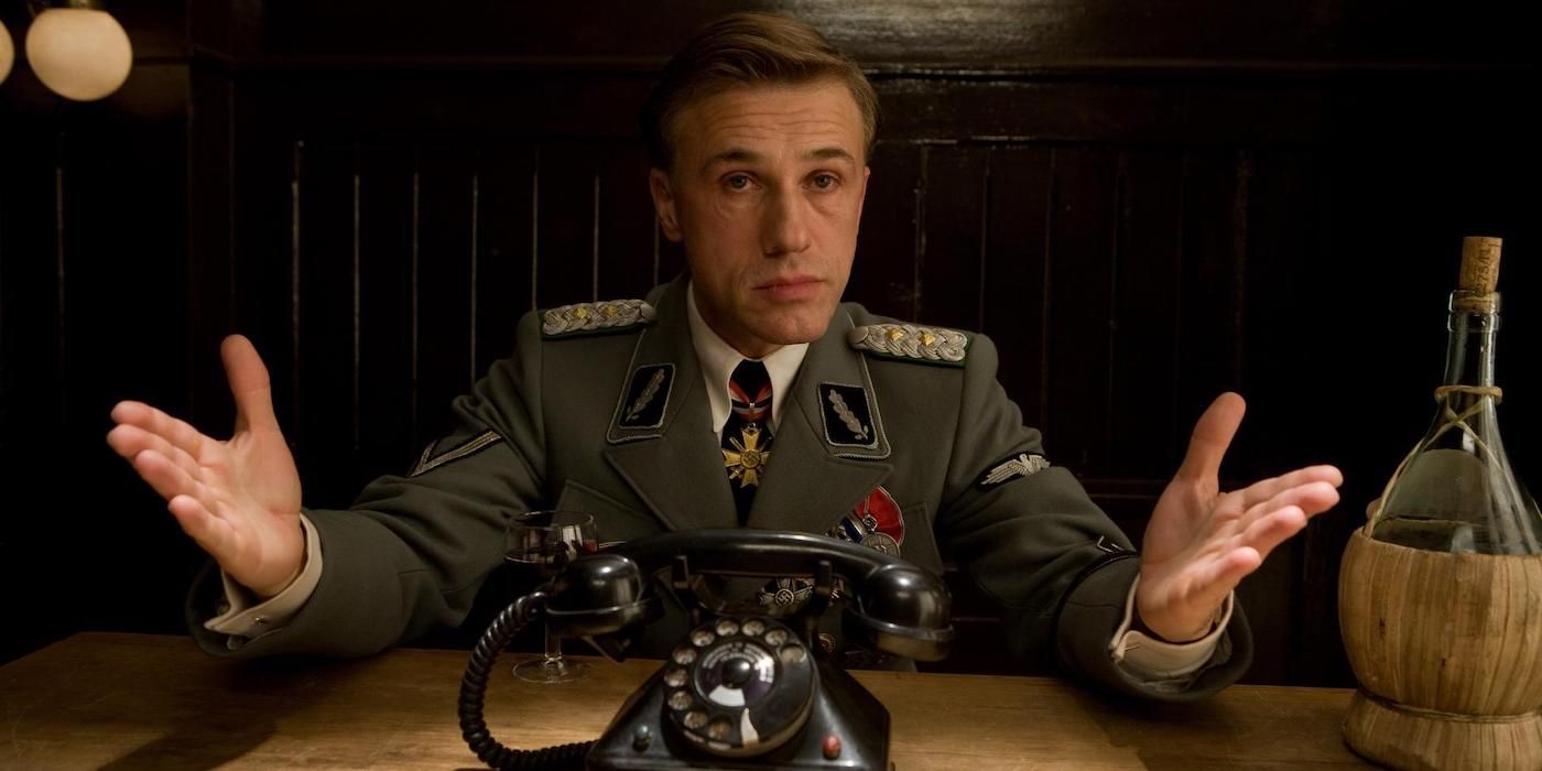 Christoph Waltz sits at a desk with a phone on it in Inglourious Basterds