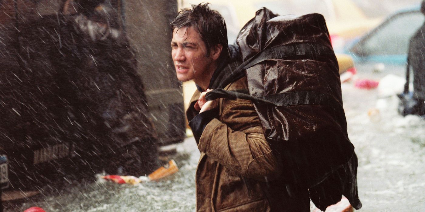 Jake Gyllenhaal in The Day After Tomorrow carrying a bag while it rains.