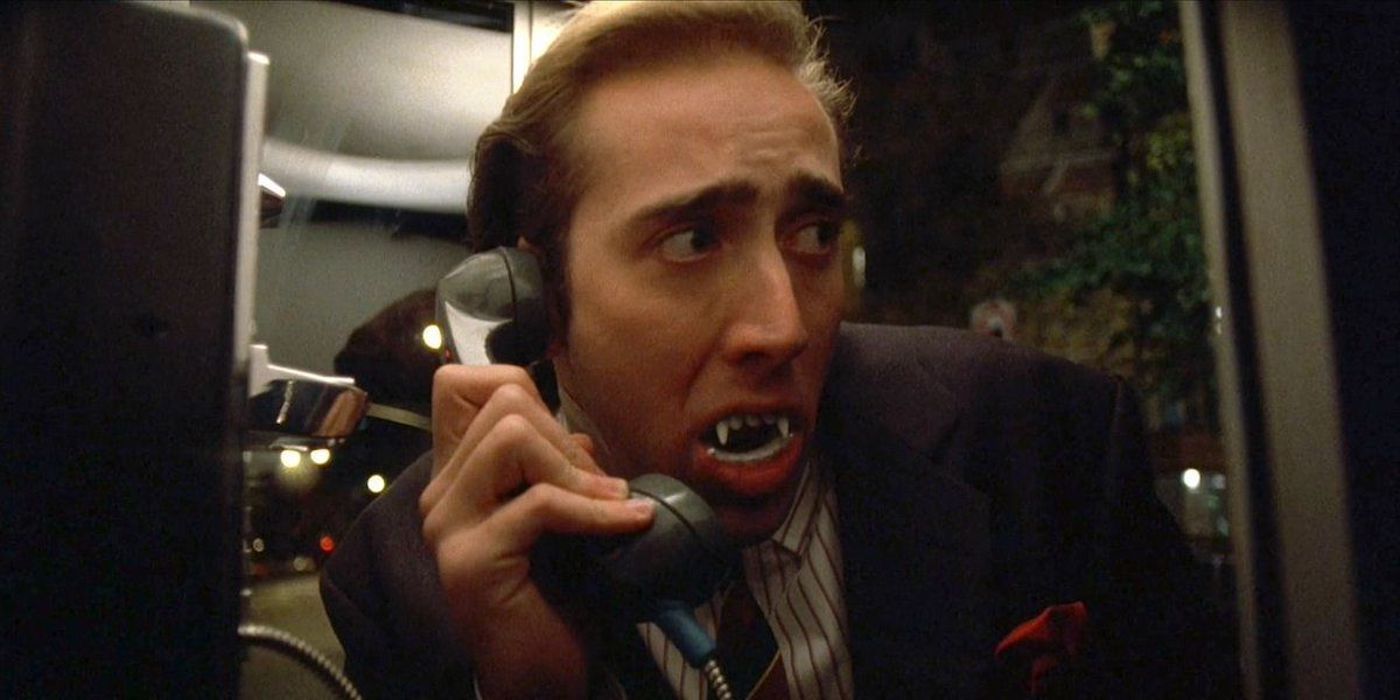 Nicolas Cage as Peter with fangs in a phone booth looking scared in Vampire's Kiss.