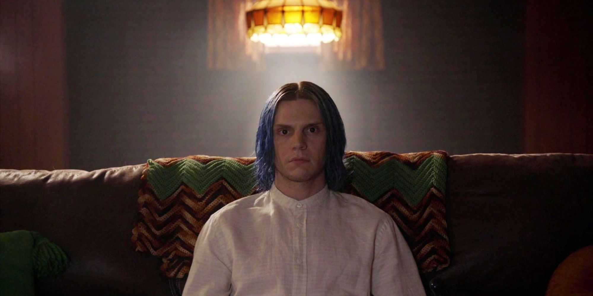 Evan Peters as Kai Anderson wearing a white polo and watching TV in 'American Horror Story: Cult'