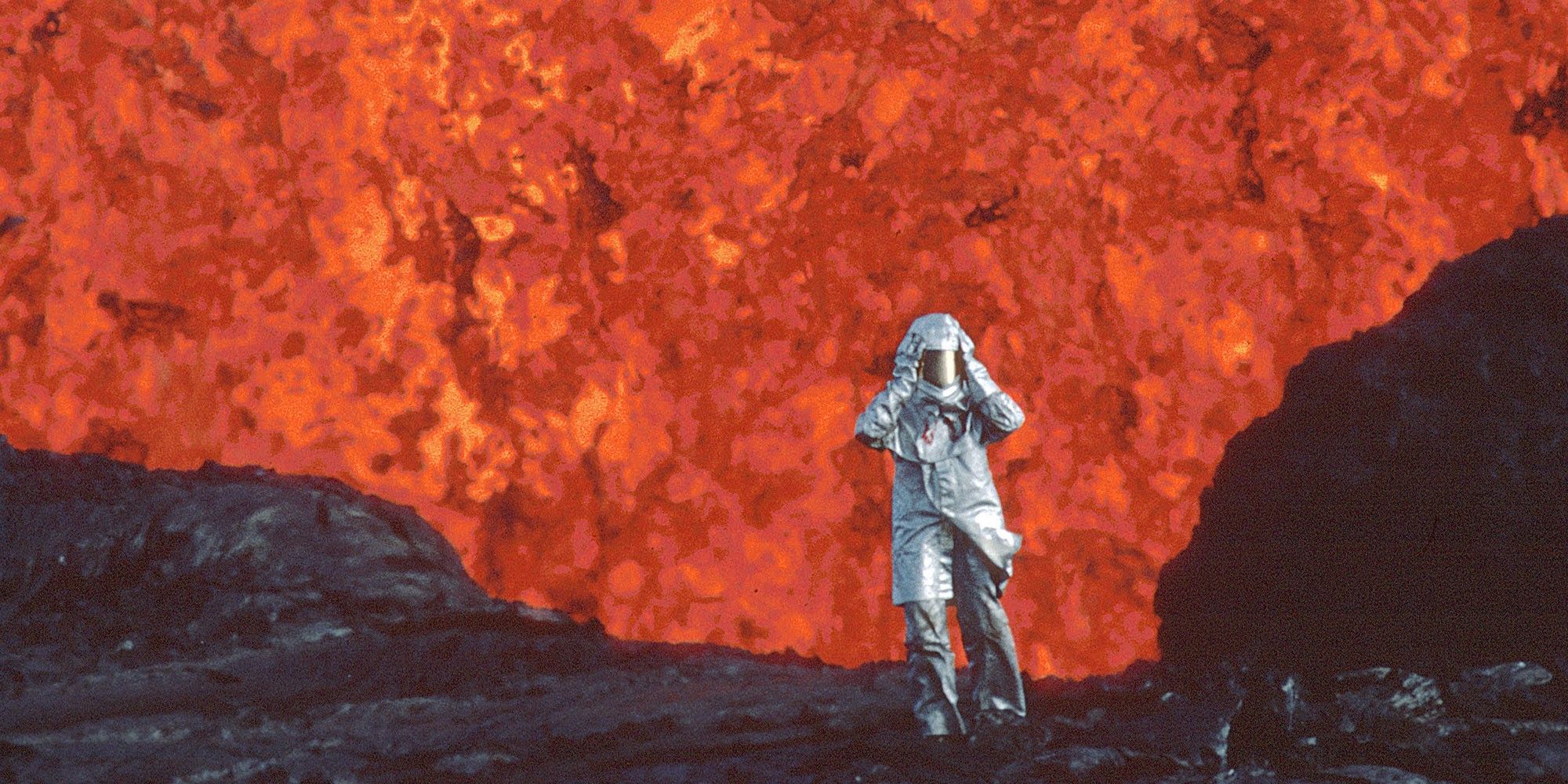 A person walking with a wall of lava in the background in the documentary Fire of Love.