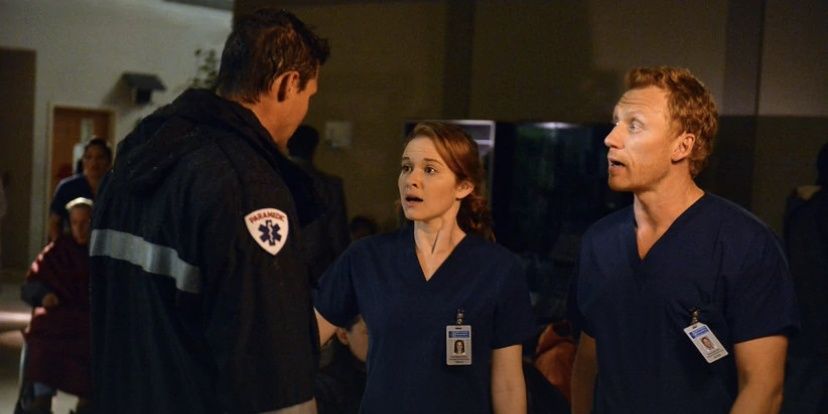 A paramedic talking to Sarah Drew as Dr. April Kepner and Kevin McKidd as Dr. Owen Hunt in a dark hospital in Greys-Anatomy, The Perfect Storm episode
