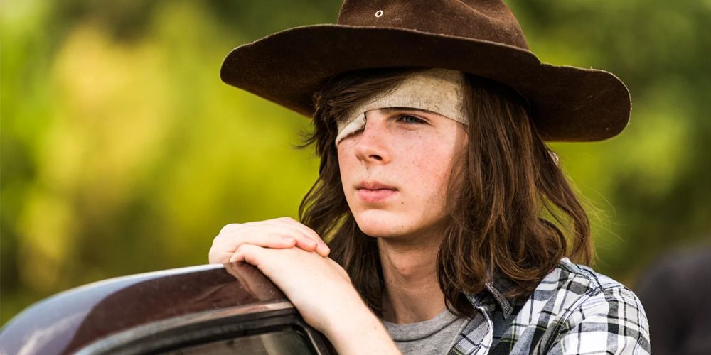 A wounded Carl Grimes wears his father's hat as he looks over a car door in 'The Walking Dead'