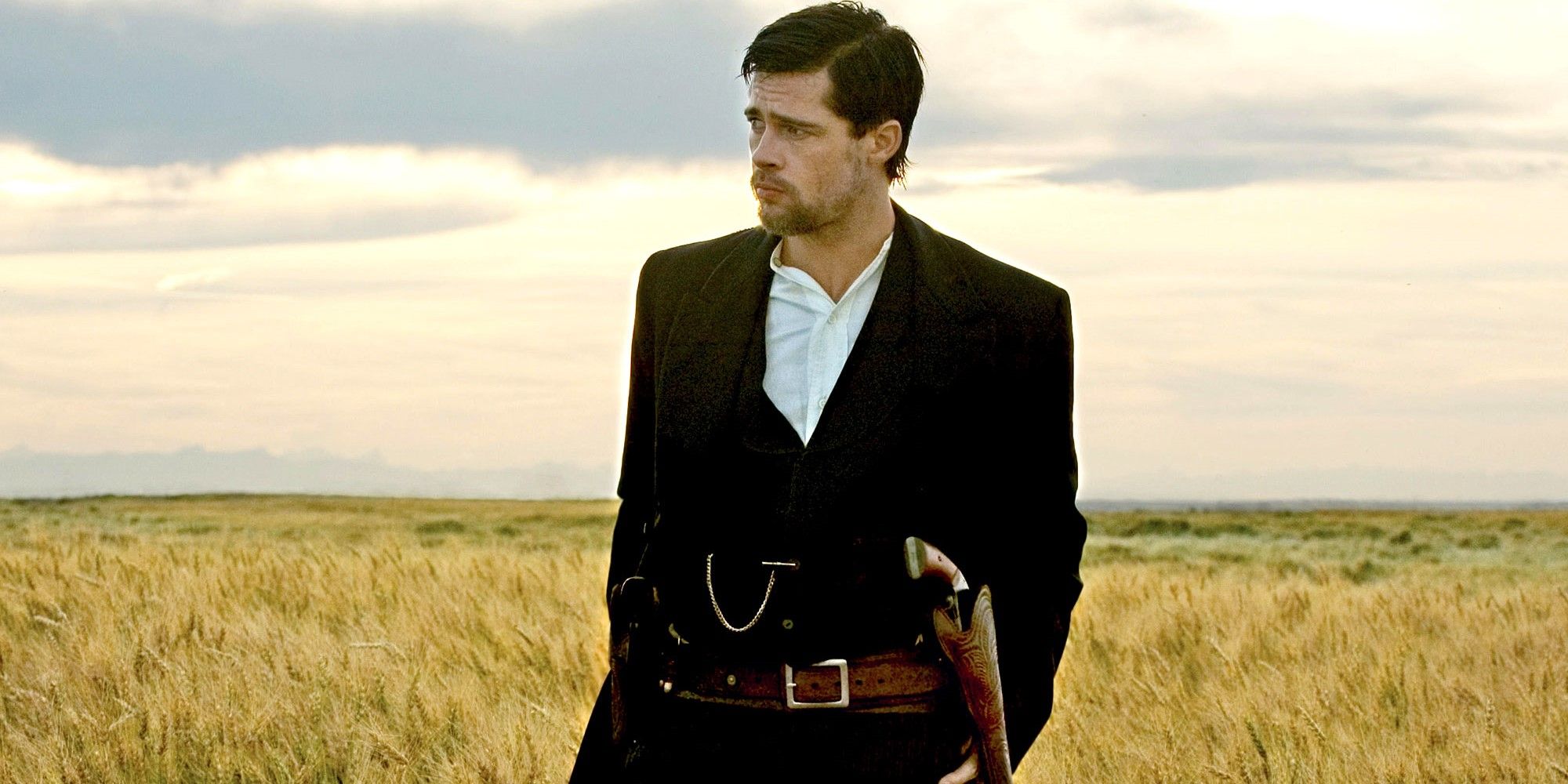 Jesse James (Brad Pitt) stands in a field with his gun at his hip, looking out meditatively across the range.