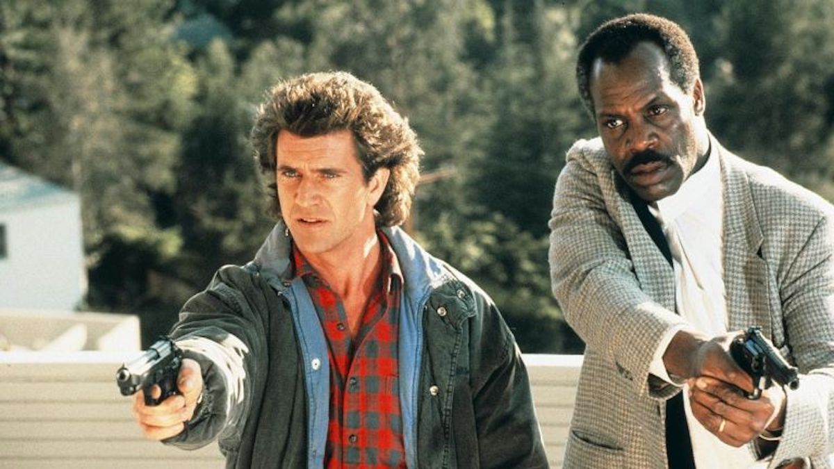 Mel Gibson as Martin Riggs aiming a gun with Danny Glover as Roger Murtaugh in Lethal Weapon