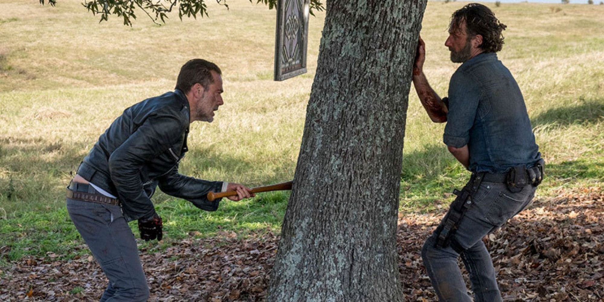 Two men evade each other around a tree, one holding a baseball bat in The Walking Dead Season 8 episode Wrath.