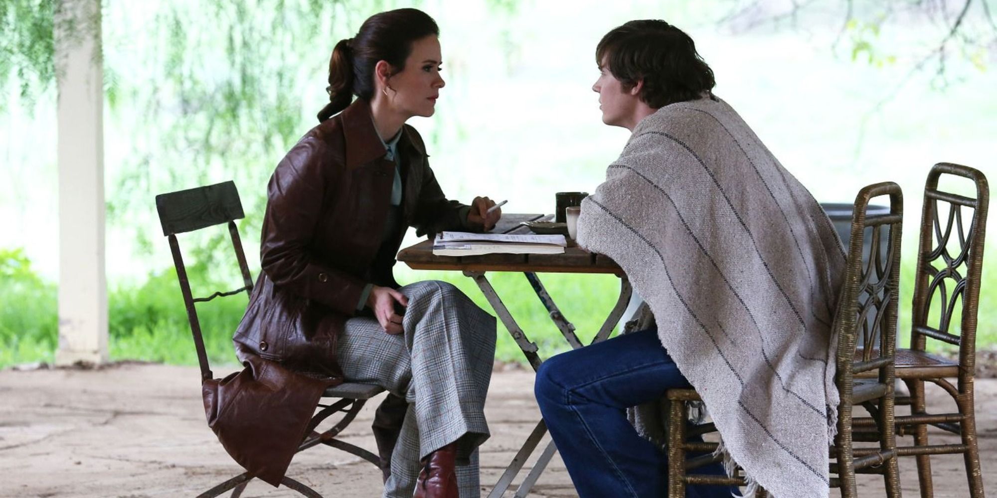 Sarah Paulson as Lana Winters and Evan Peters as Kit Walker in 'American Horror Story: Asylum', sitting at a table with notes.