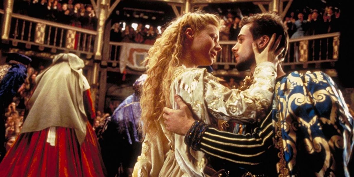 Viola and Will staring into each other's eyes while on a stage surrounded by people in Shakespeare In Love.