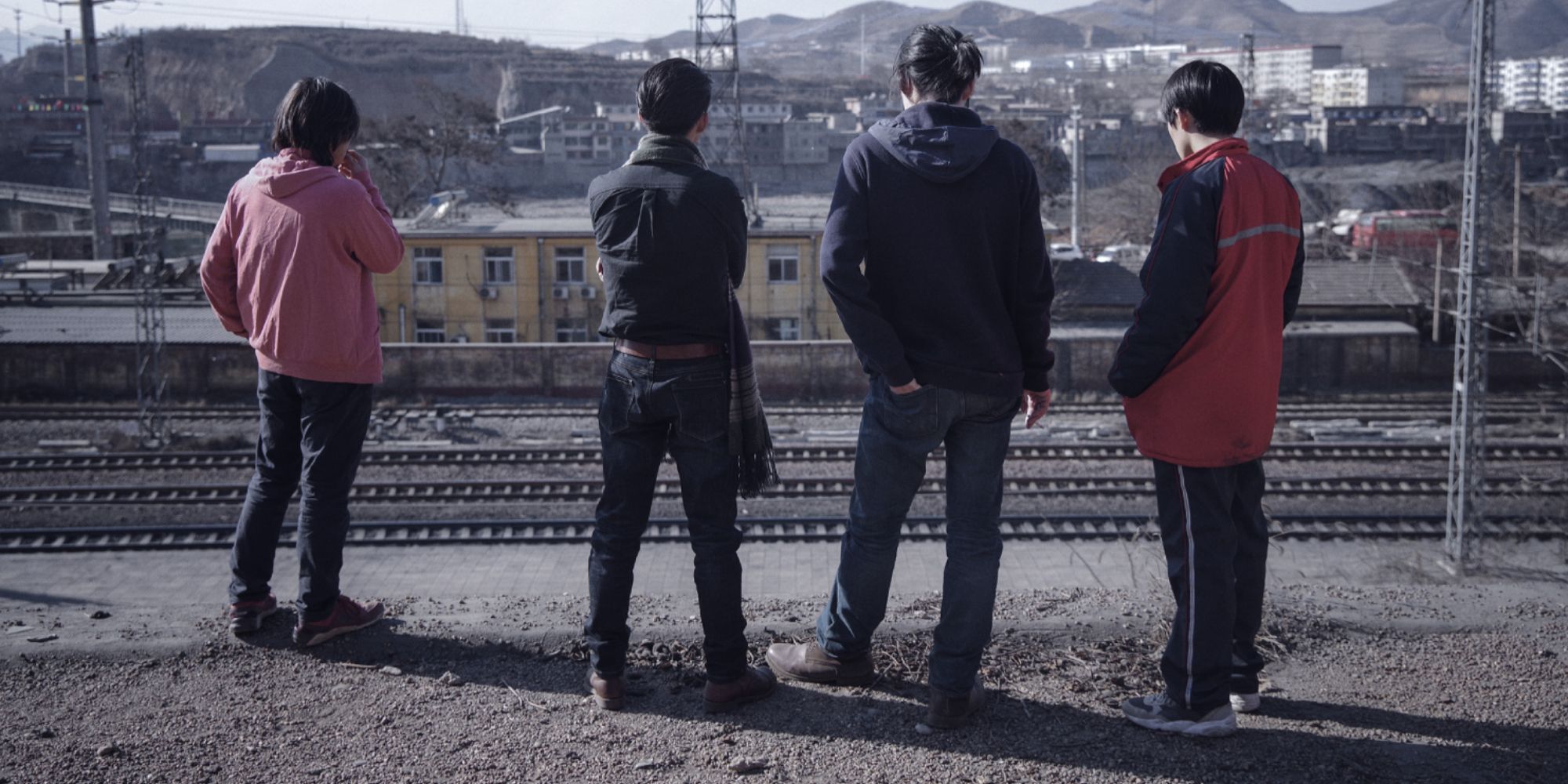 Four figures with their back to the camera looking towards a slum in An Elephant Sitting Still