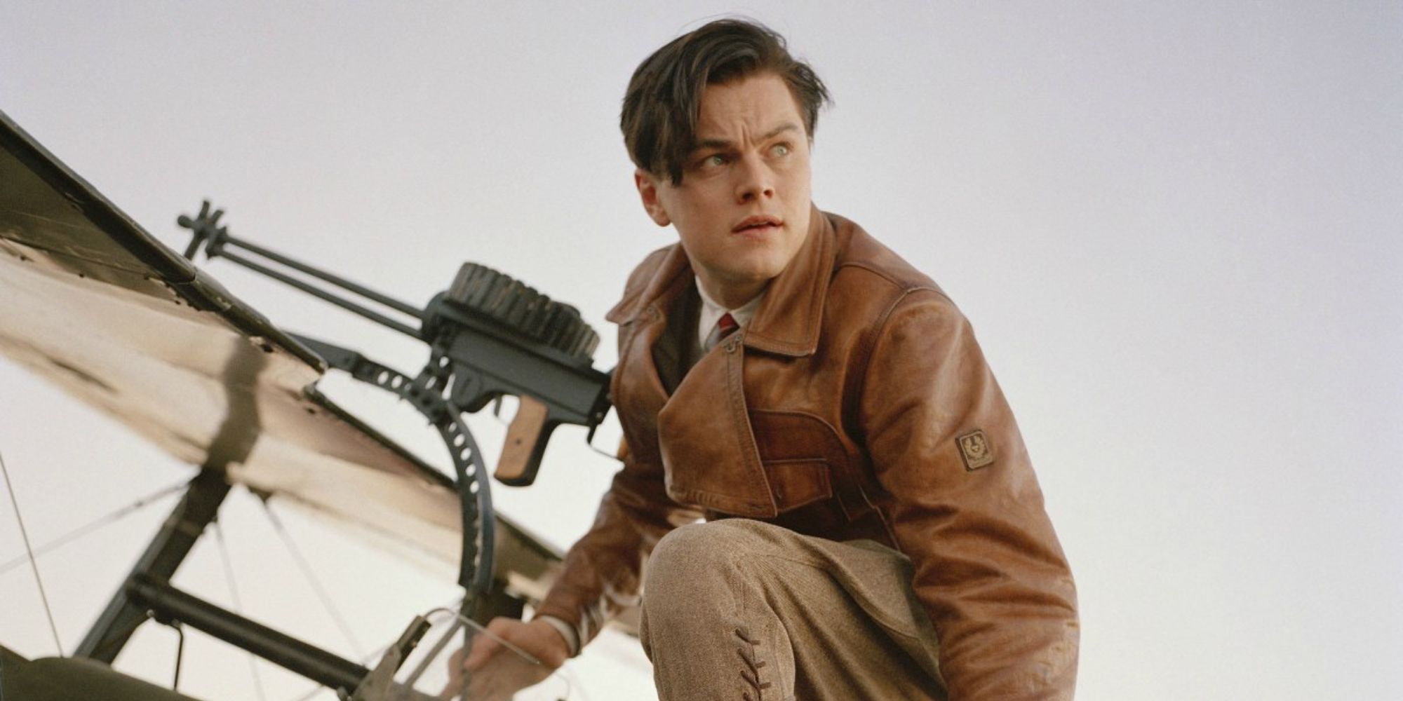 Leonardo DiCaprio kneeling next to a plane in The Aviator