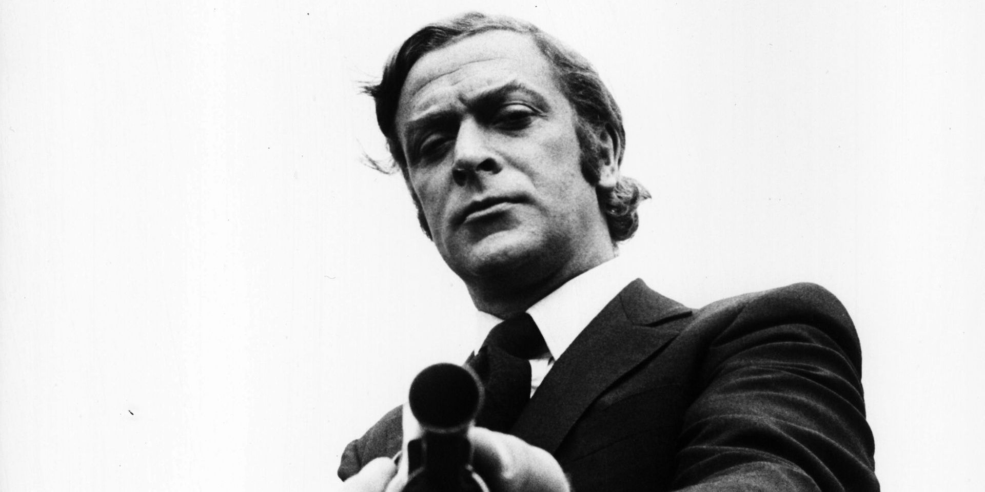 Michael Caine as Jack Carter pointing a gun in Get Carter