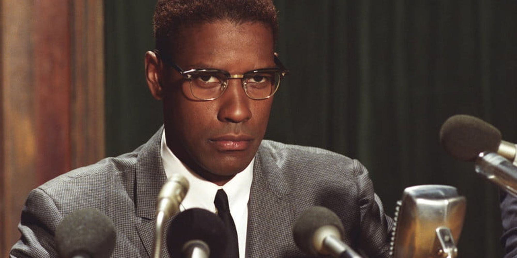 Denzel Washington assis derrière des micros dans Malcolm X