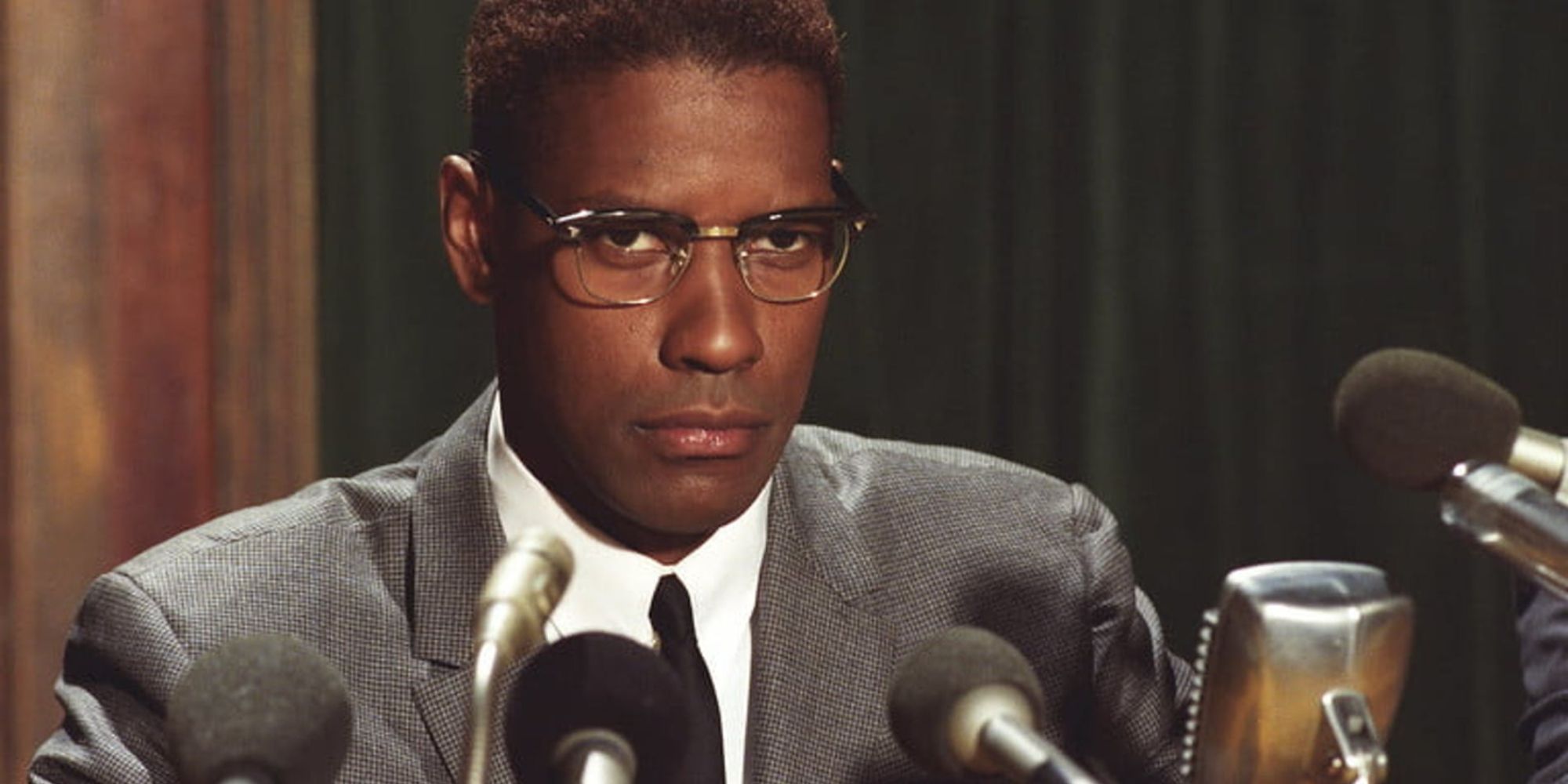 Denzel Washington sitting behind microphones in Malcolm X