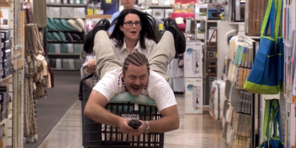 Megan Mullally poussant Nick Offerman dans un trolley dans Parks and Recreation.