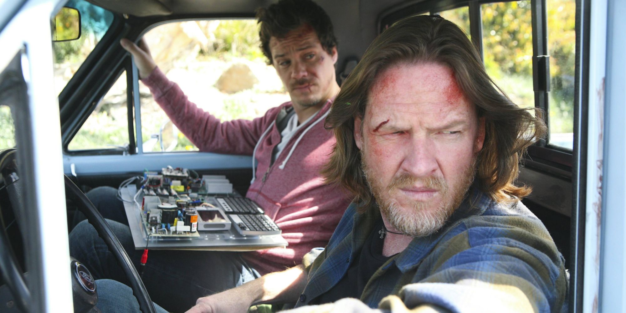 Two men sitting in a car, one with blood on his face in Terriers.