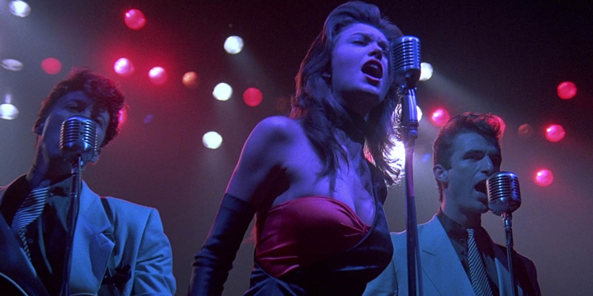 Two men and a woman singing on stage in the film Streets of Fire