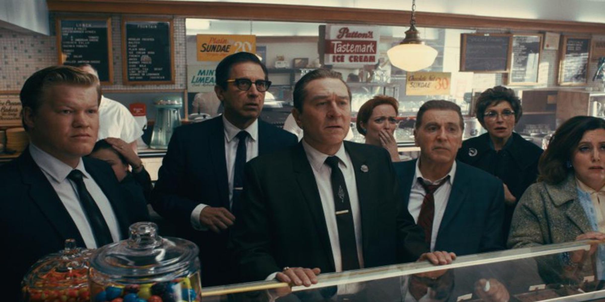 Jesse Plemmons, Ray Romano, Robert De Niro, and Al Pacino watching the TV in a store in The Irishman