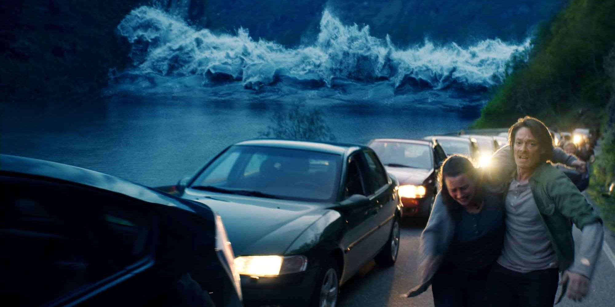 Gerry helps a woman down an abandoned road as a large wave approaches