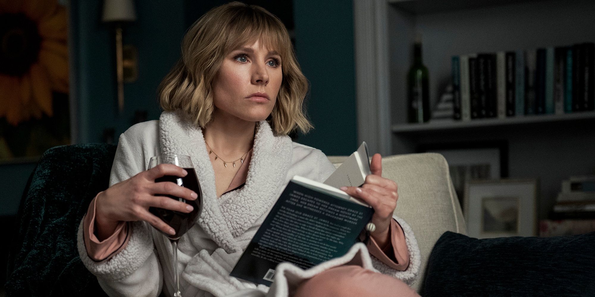 Emma staring intently at something while she holds a glass of wine and a book