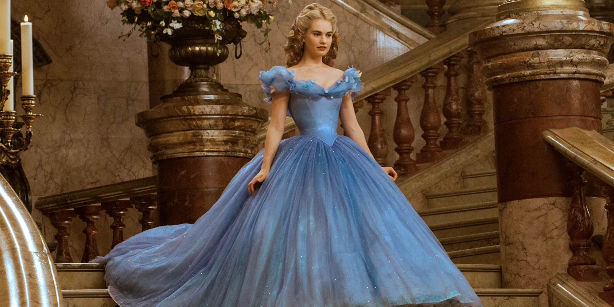Lily James as Ella/Cinderella walking down a set of stairs wearing her blue gown in Cinderella
