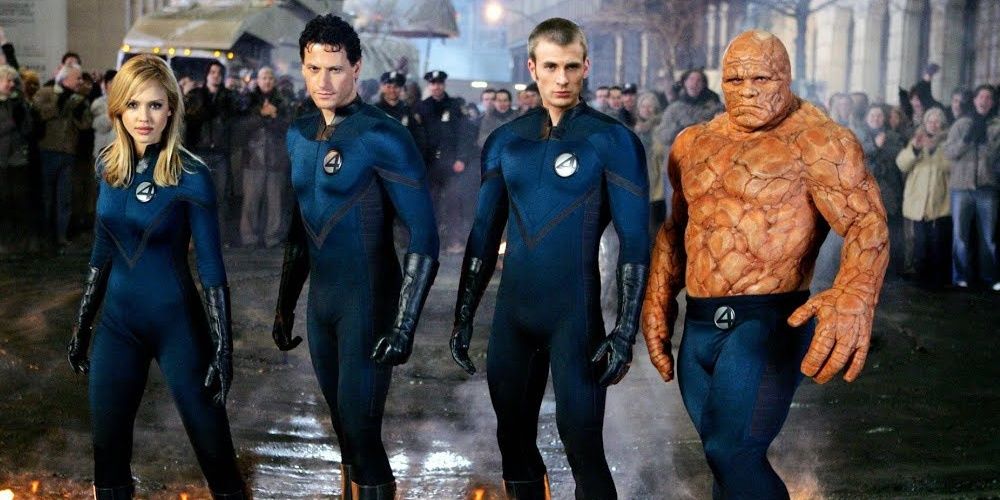 All four members of the Fantastic Four stand side by side on road with pedestrians watching