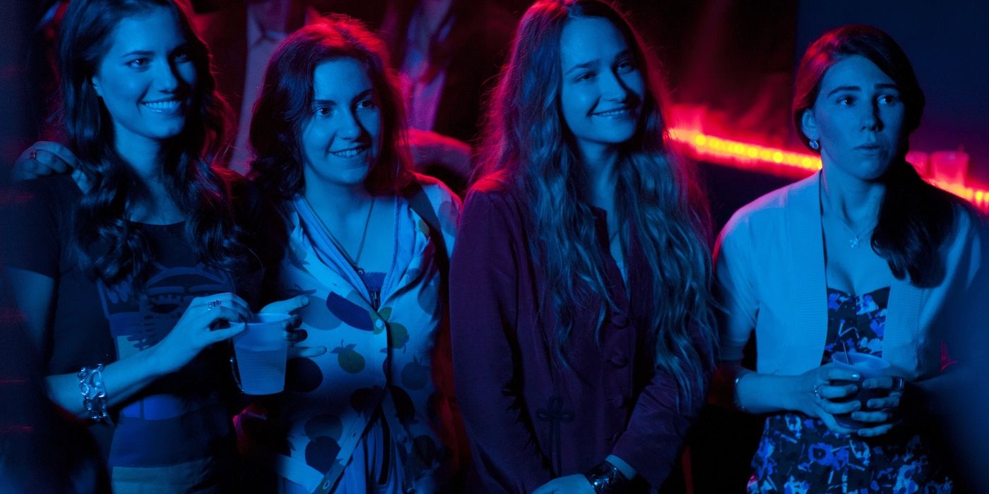 The four main characters from Girls smiling at a club.