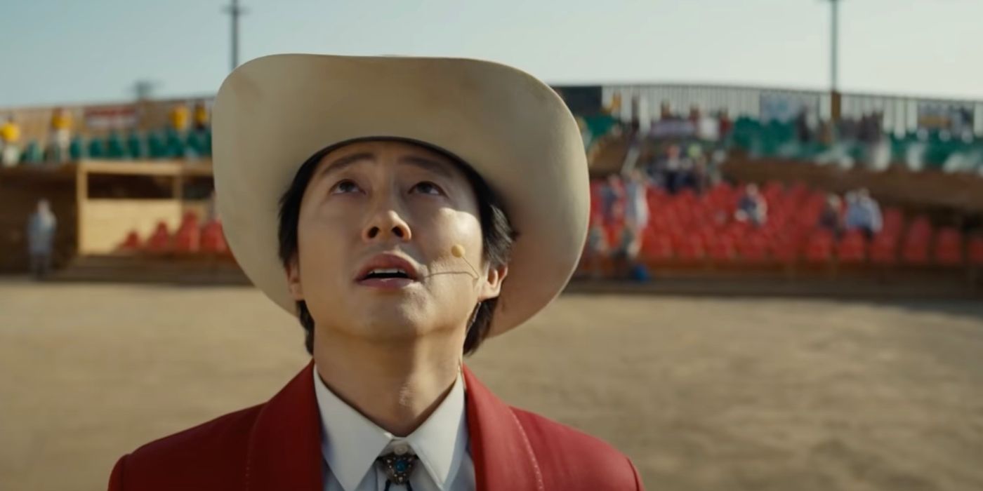 Steven Yeun as Jupe looking up with a shocked expression while at a rodeo ring in Nope