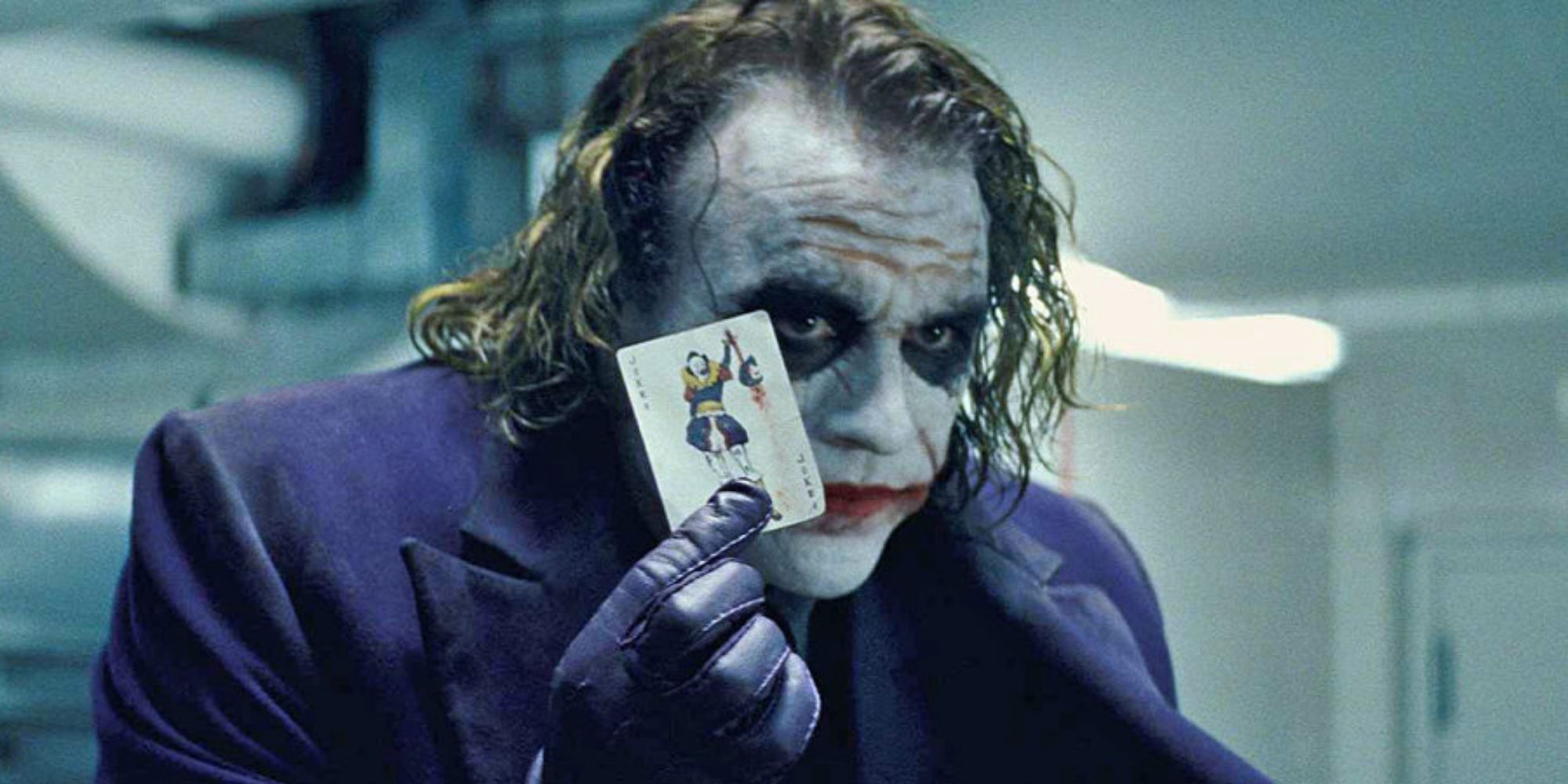 The Joker raising a card in The Dark Knight.