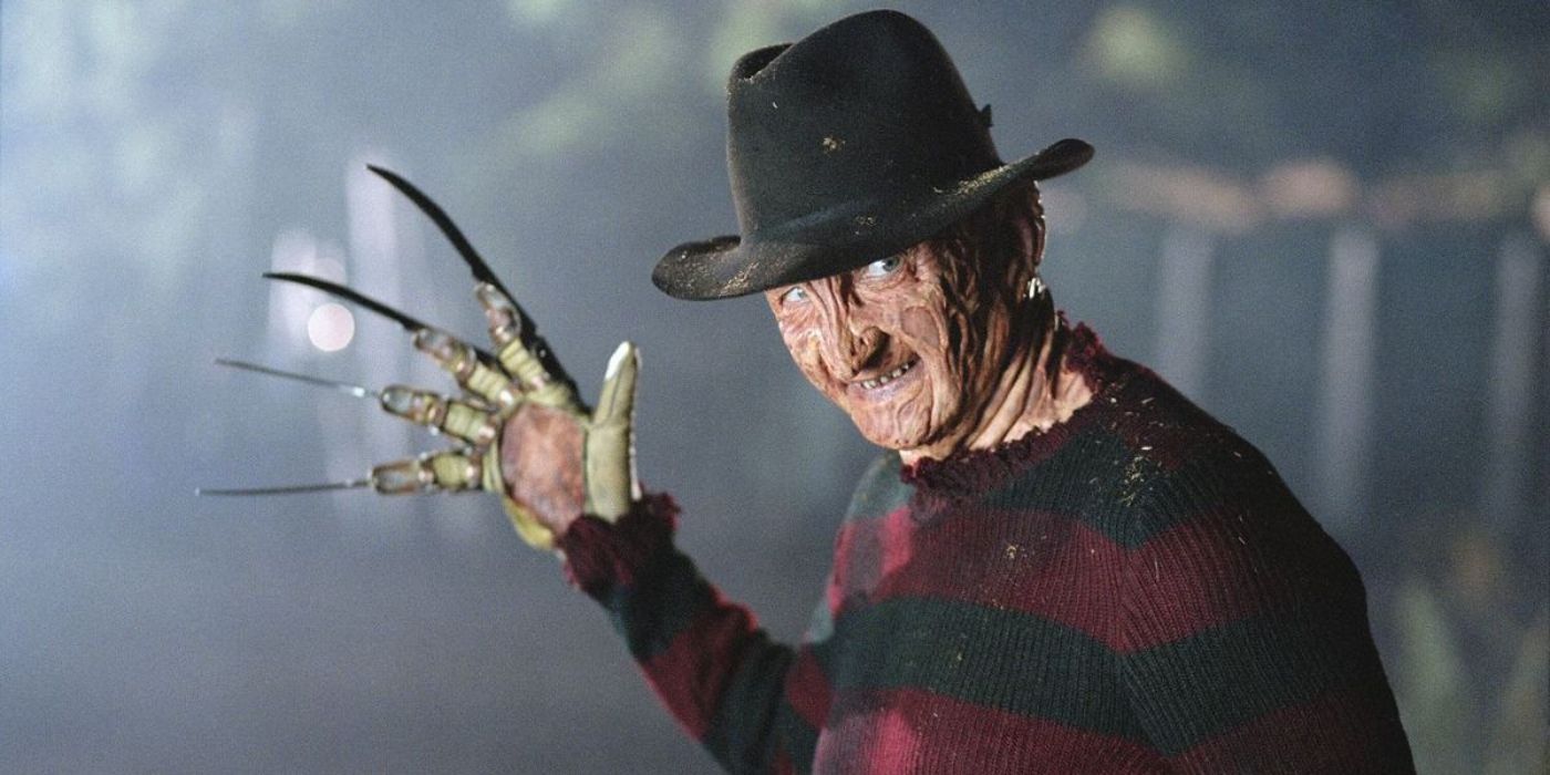 Freddy Krueger (Robert Englund) smiling and holding his gloved hand out in A Nightmare on Elm Street