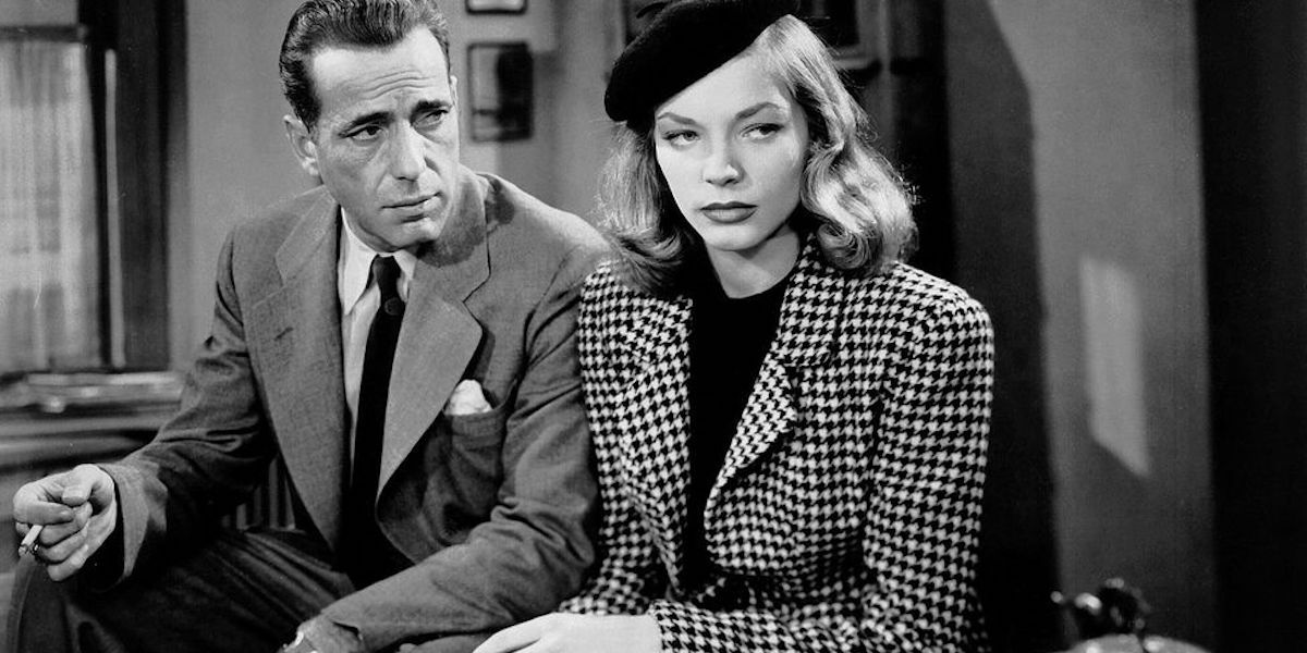 Humphrey Bogart duduk di sebelah Lauren Bacall dan menatapnya Tidur Besar
