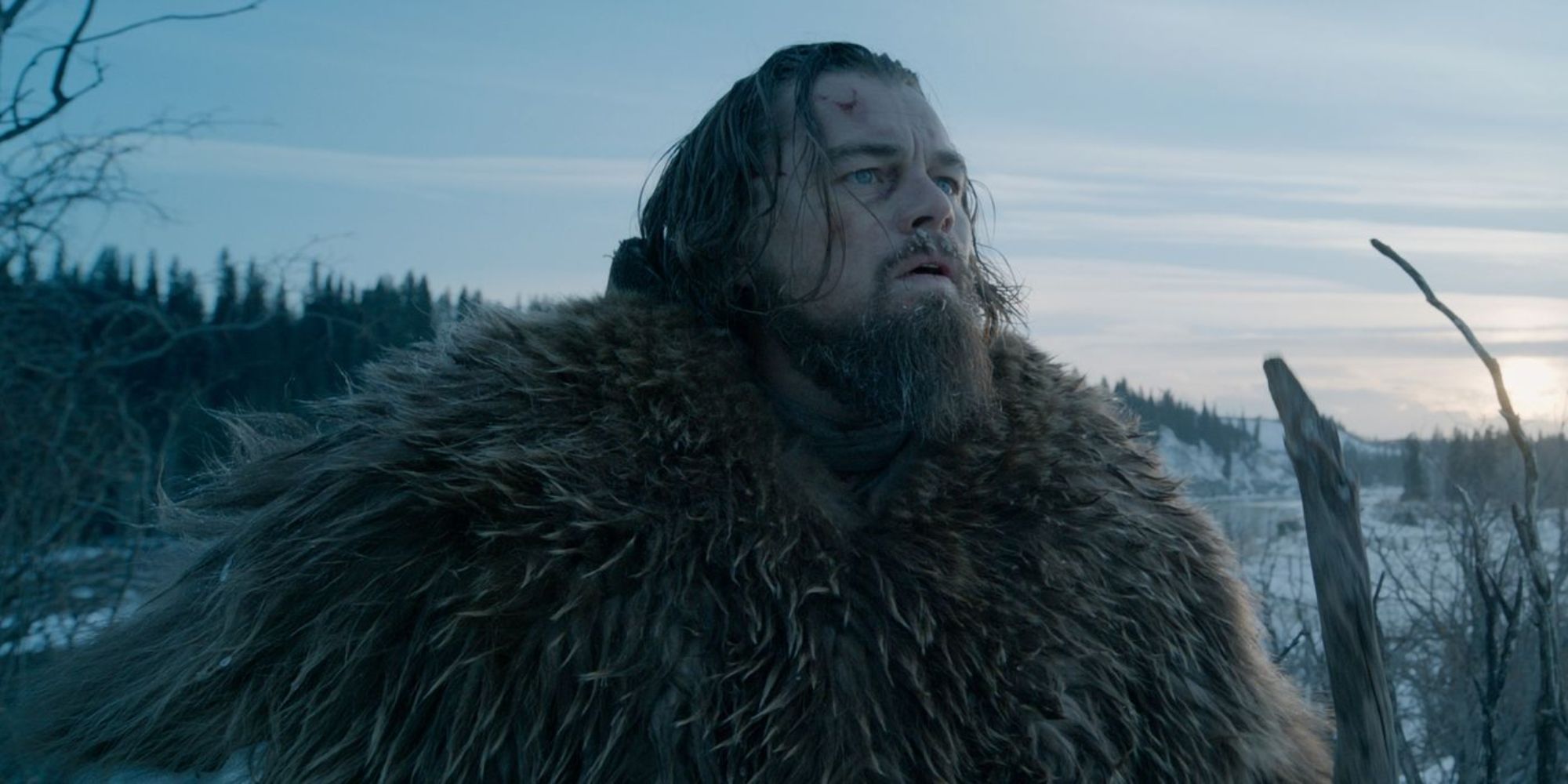 Leonardo DiCaprio as Hugh Glass in a thick fur coat looking to the distant wilderness in The Revenant.