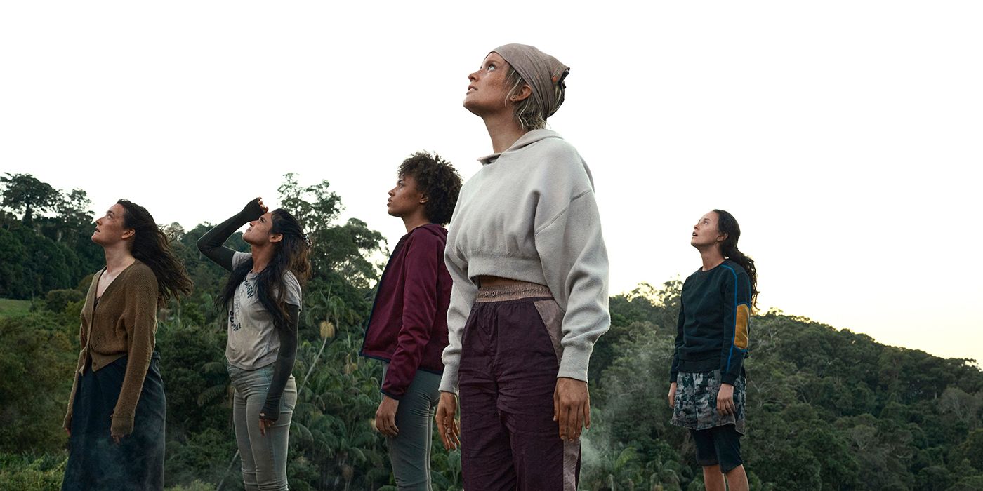 A group of teenage women looking up into the sky while in the wild in a scene from The Wilds.