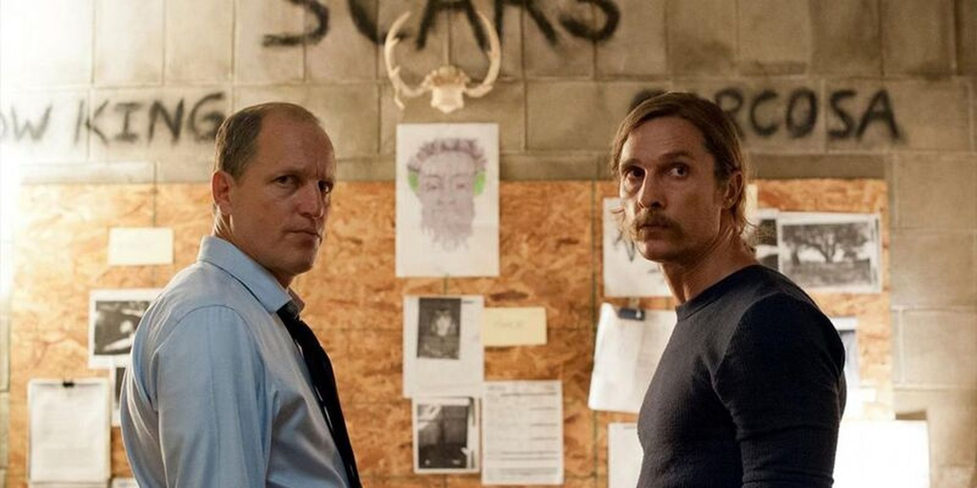 Marty and Rust looking in the same direction with an evidence board behind them in True Detective.