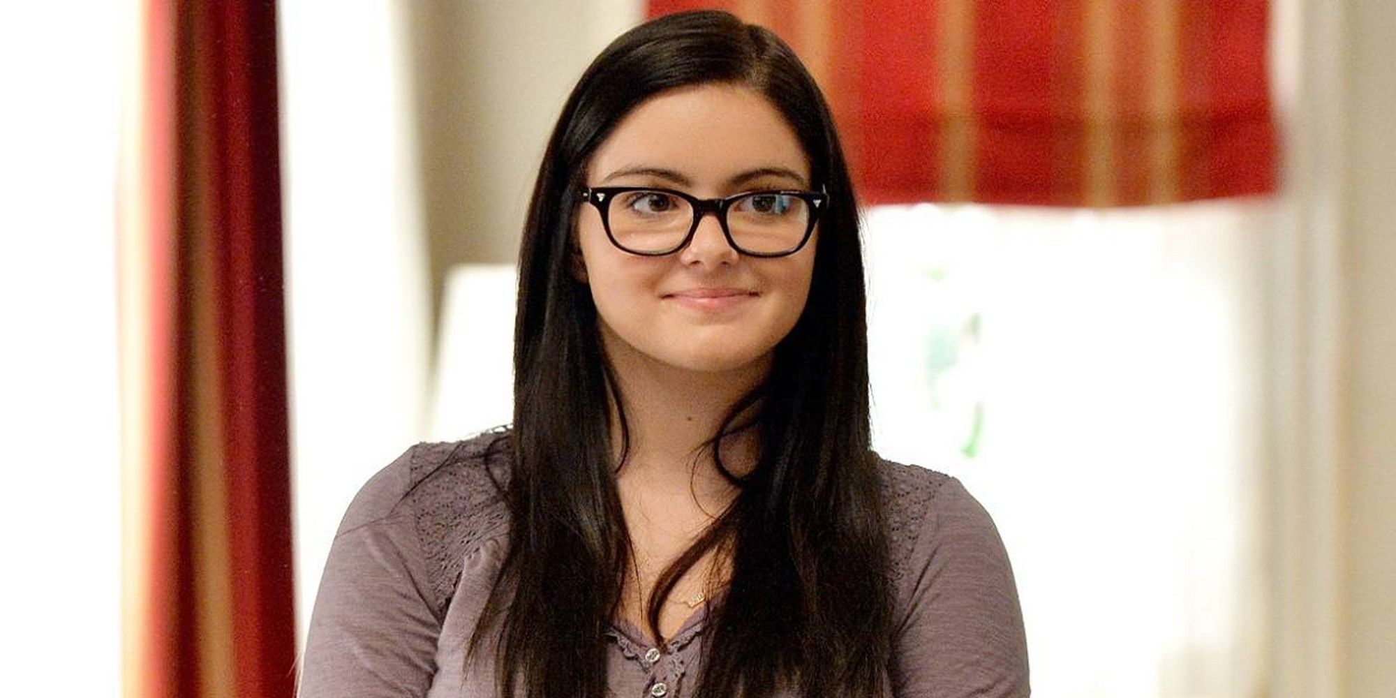 Ariel Winter as Alex Dunphy smiling and looking off-camera in Modern Family.