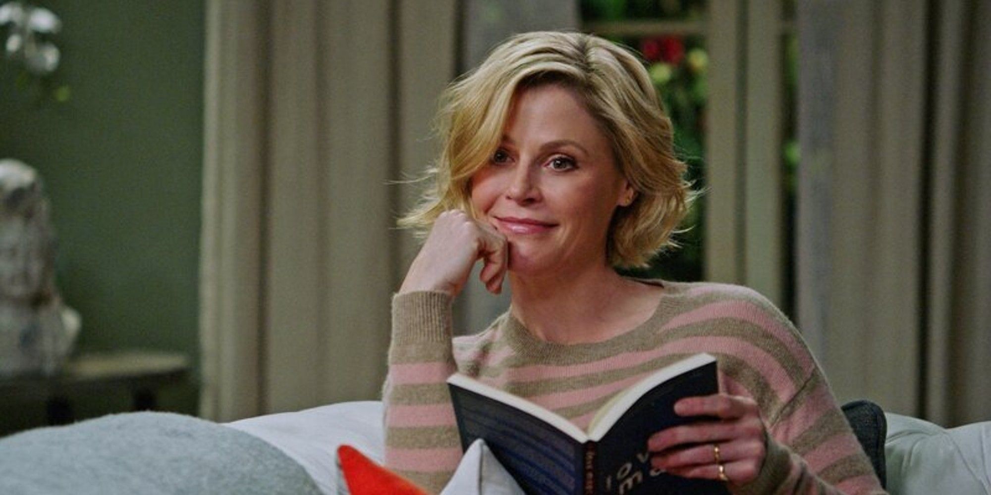 Julie Bowen as Claire Dunphy smiling while holding an open book in Modern Family