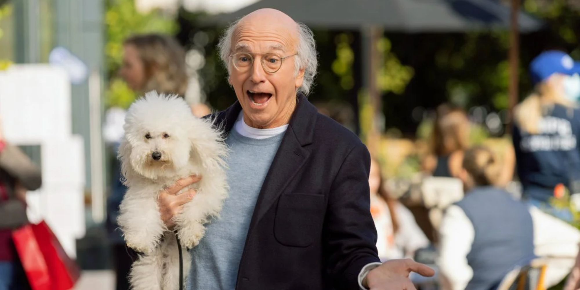 Larry David holding a dog and smiling on Curb Your Enthusiasm